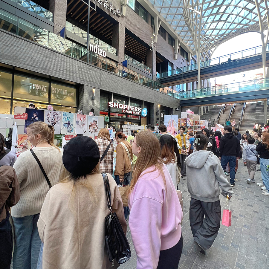Crowds of visitors enjoying The Well Toronto’s Surprise Carnival Market 2025 under the glass atrium, browsing vendors and local artist booths.