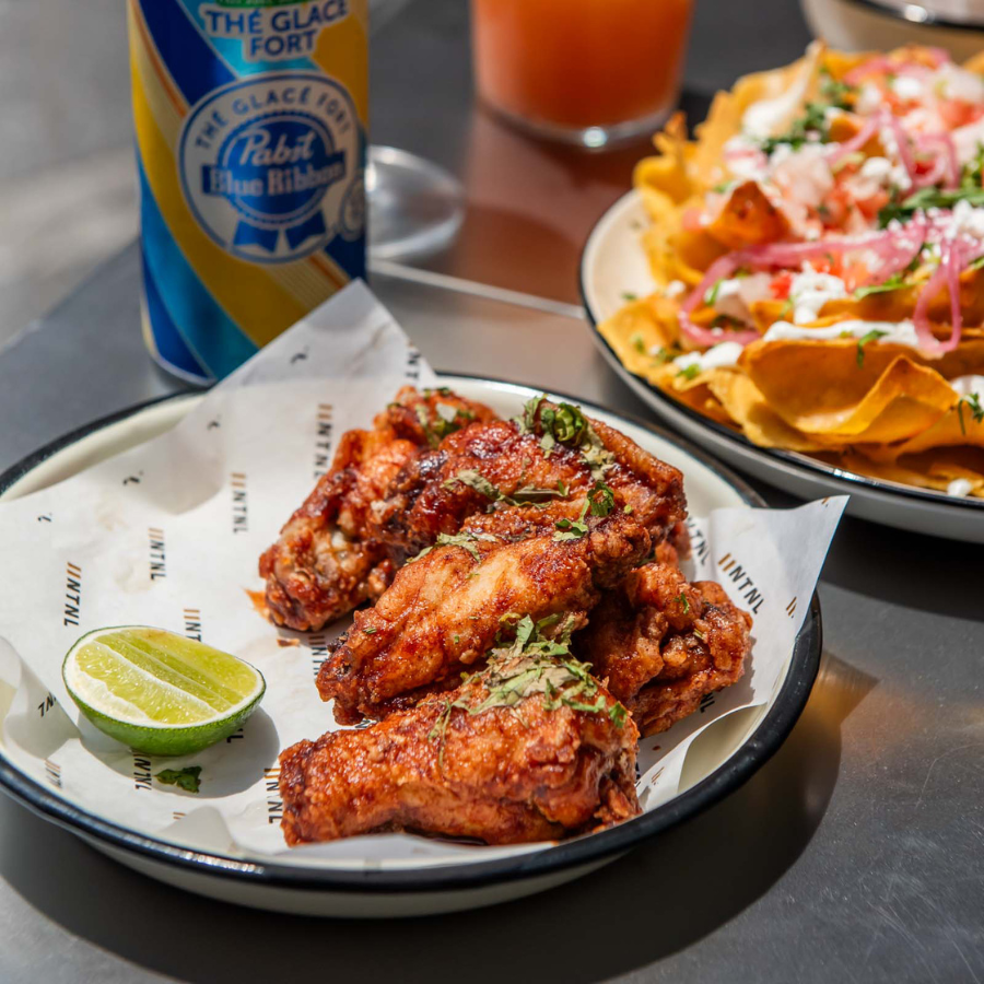 Basket of chicken wings with nachos and Bud Light pint for Game Day specials at National The Well Toronto
