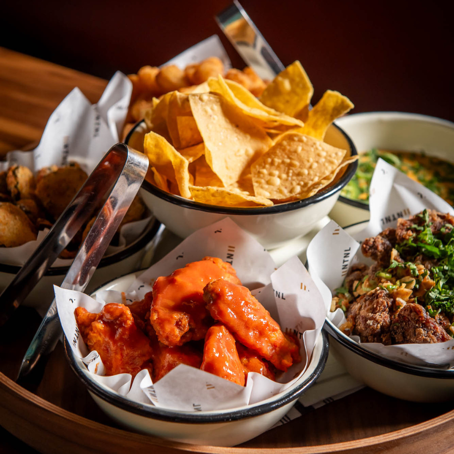 Platter of game day food with sliders, wings, fries, and appetizers at National The Well in Toronto