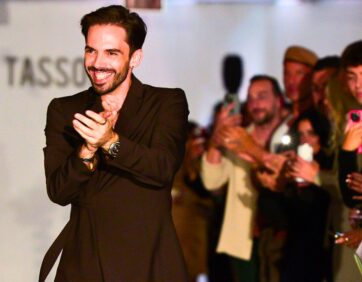 Designer Joseph Tassoni on stage applauding with the audience during The Intersection of Style & Tech fashion show at The Well in Toronto.