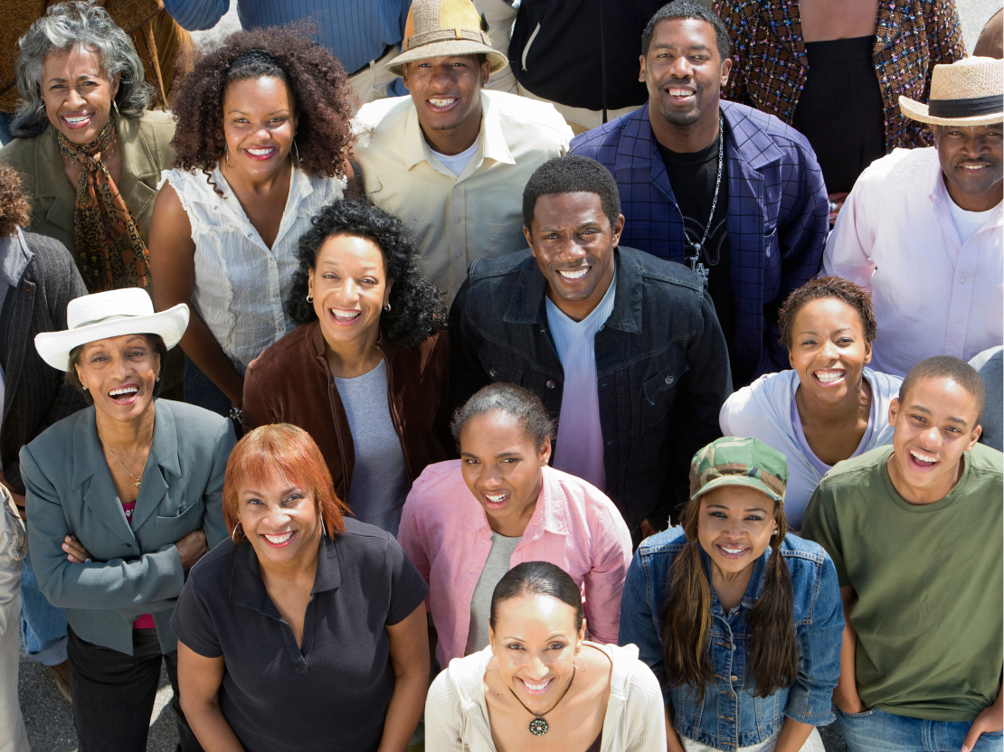 A diverse group of smiling people gathered together at a wellness and community event.
