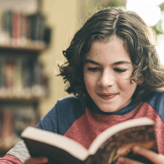 Woman smiling while reading a book in a cozy bookstore setting.